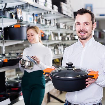 Male salesman helps to choose new kitchen utensils for customers in the store Male salesman helps to choose new kitchen utensils for customers in the store